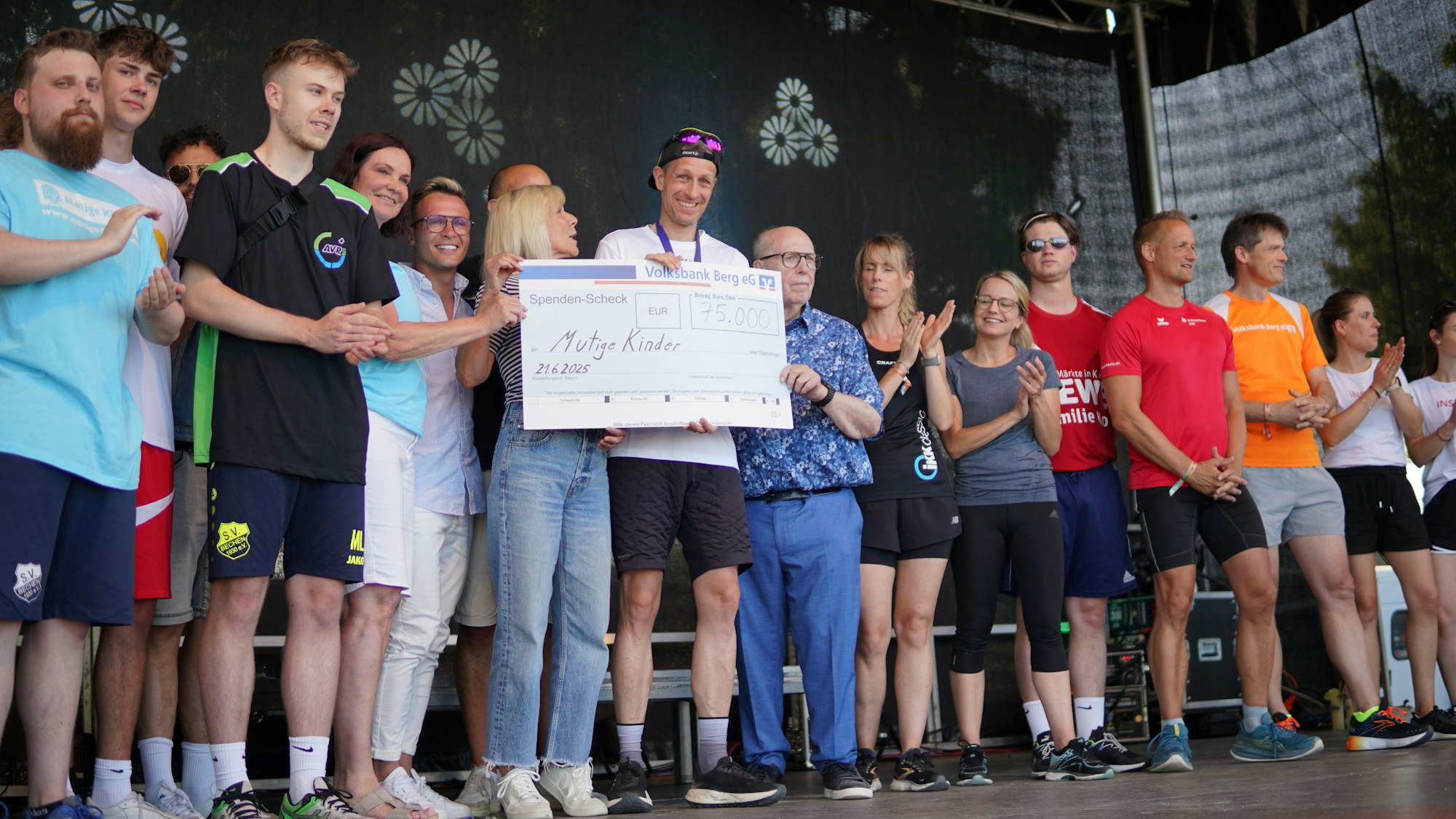 Sascha Gramm überreicht einen Scheck an Reiner Calmund.