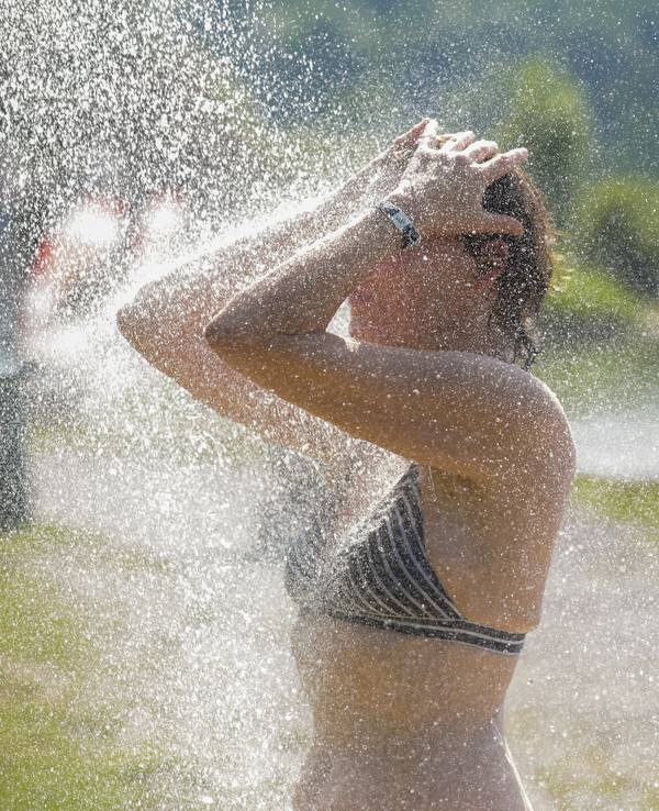Eine Frau kühlt sich bei sommerlichen Temperaturen unter einer Dusche am Schwarzachtalsee ab.