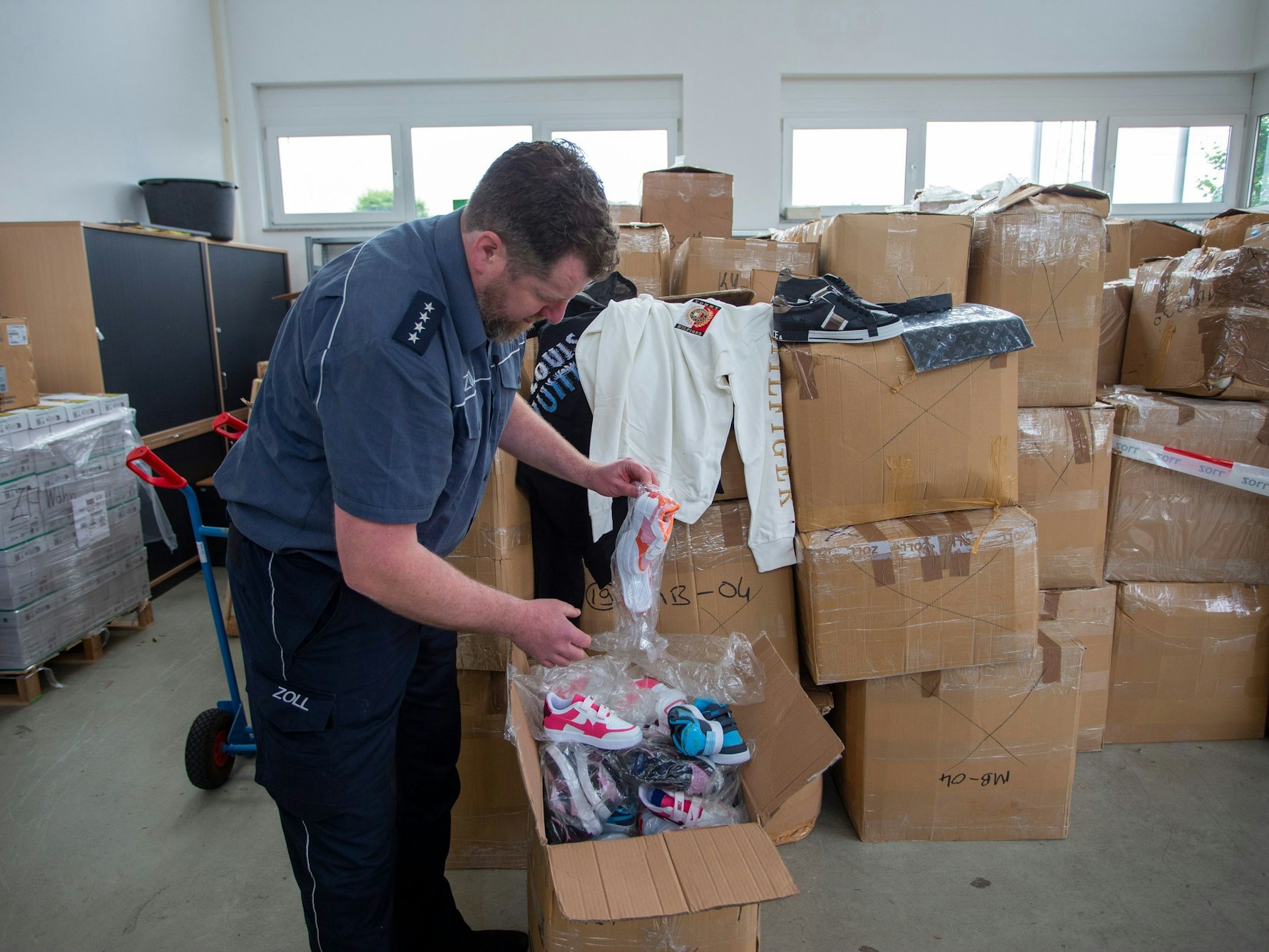 Ein Mann steht vor einem geöffneten Karton, in dem sich Kinderschuhe befinden.