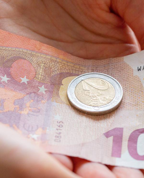 Eine Person hält 12 Euro in der Hand.