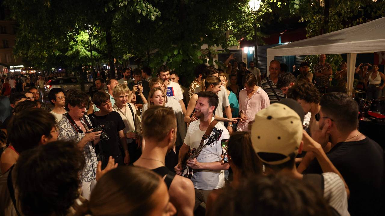 Musikbegeisterte lauschen einem Mann, der während des jährlichen französischen Straßenmusikfestivals "Fete de la Musique" im 4. Arrondissement von Paris Gitarre spielt.