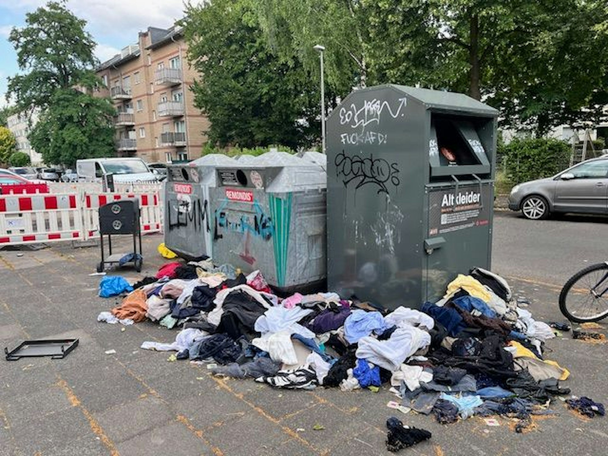 Kleidung liegt neben Containern auf der Straße.