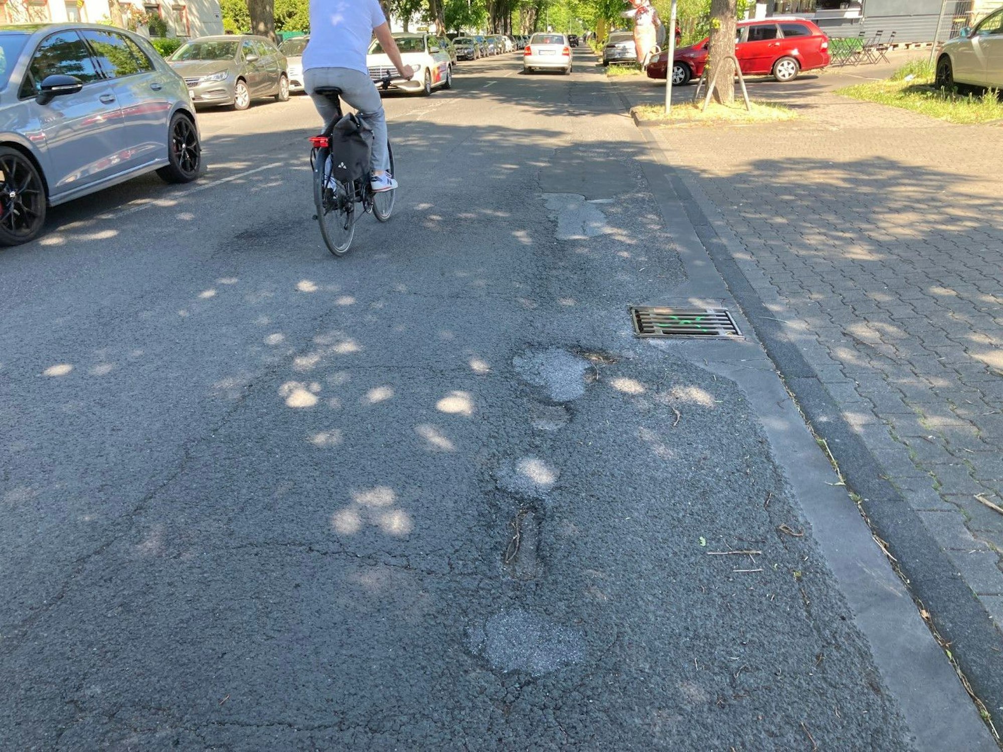 Ein Fahrradfahrer fährt über eine Straße mit Asphaltschäden.