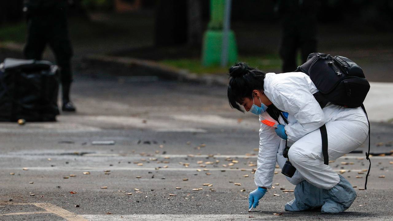 Eine Mitarbeiterin der Forensik kniet neben zahlreichen Patronen (Symbolfoto).