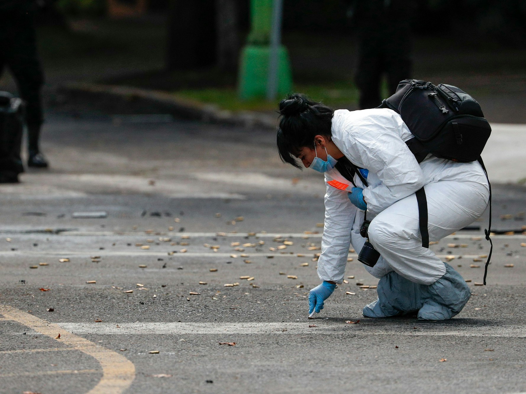 Eine Mitarbeiterin der Forensik kniet neben zahlreichen Patronen (Symbolfoto).