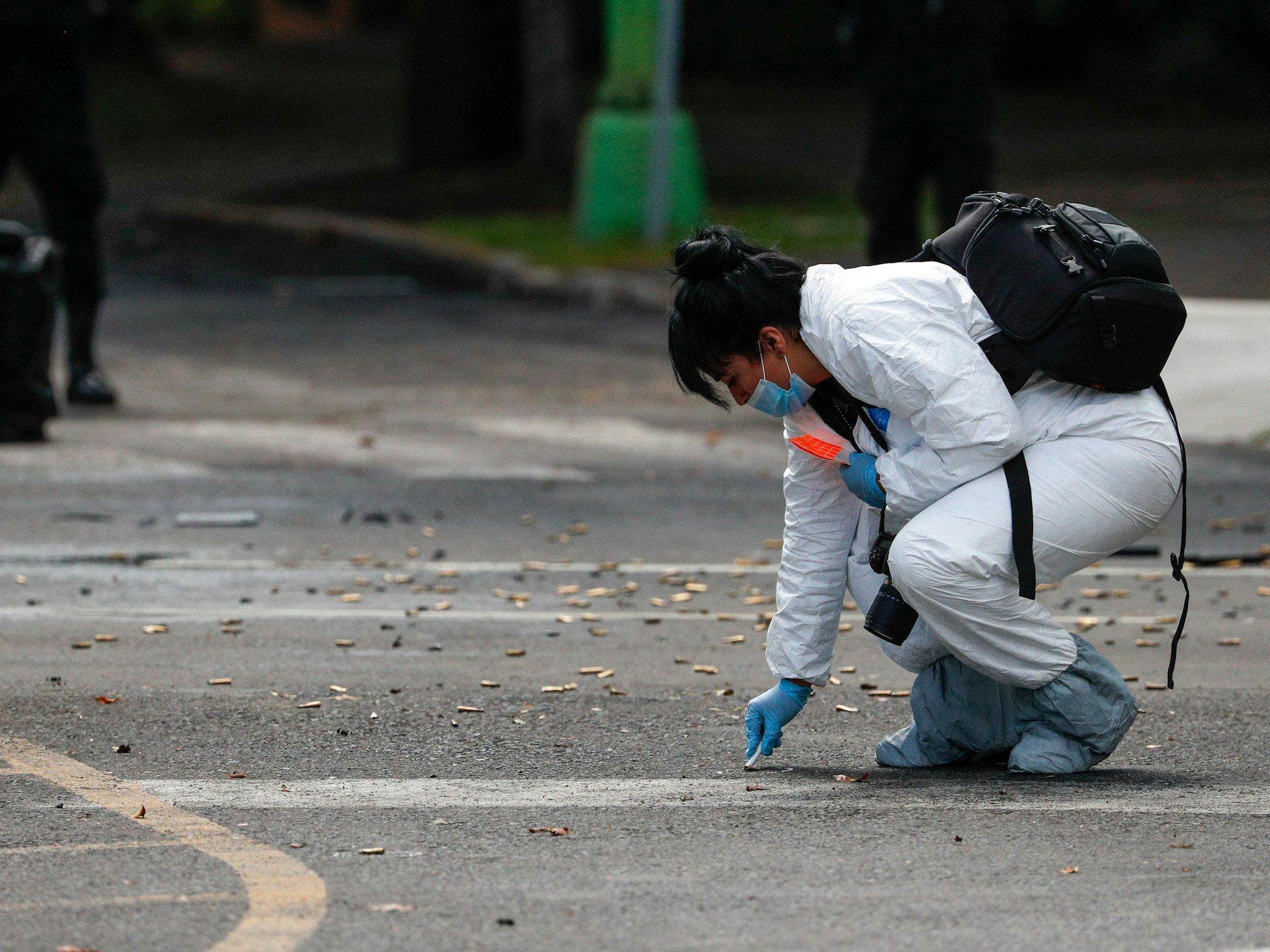 Eine Mitarbeiterin der Forensik kniet neben zahlreichen Patronen (Symbolfoto).
