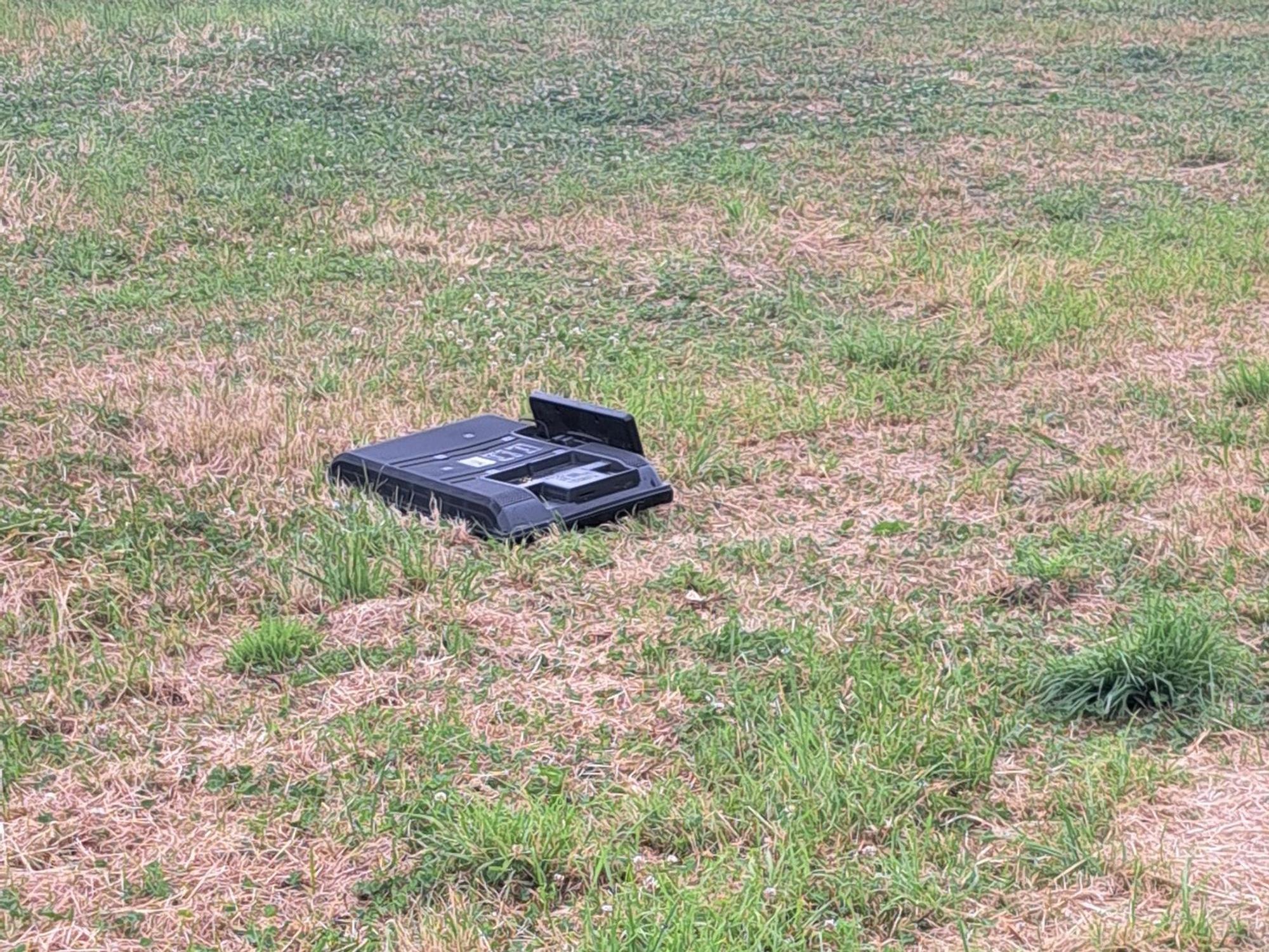 Ein Fernseher liegt auf einer Wiese.