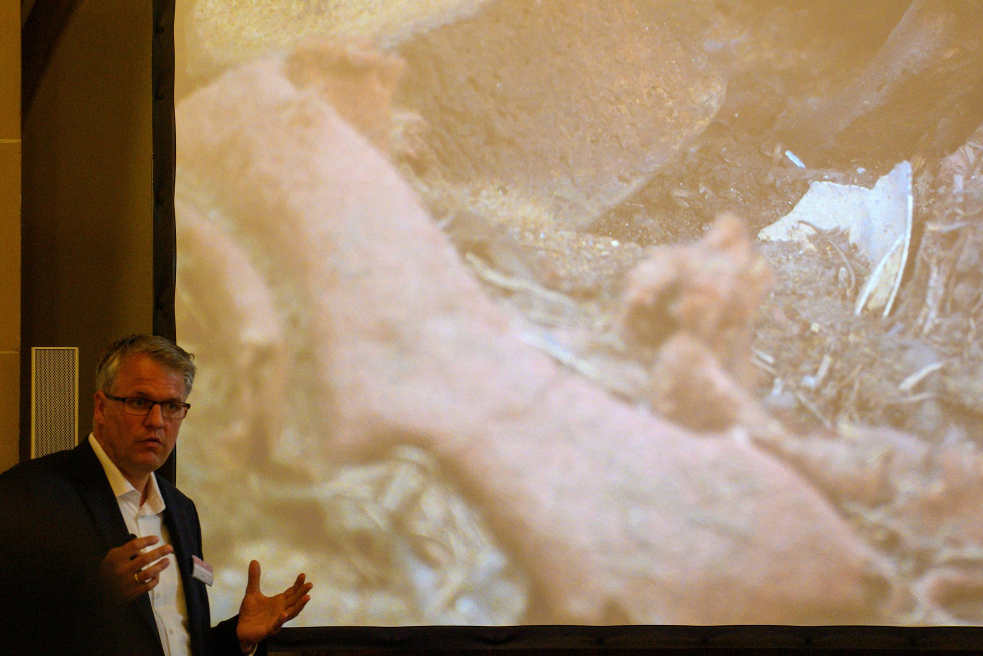 Donat Wehner (l) vom Landesamt für Denkmalpflege und Archäologie Sachsen-Anhalt erklärt in der Sakristei des Magdeburger Doms mit Hilfe einer Live-Videoübertragung aus dem Inneren der Einhausung, die das Grab von Otto dem Großen umgibt, das Inneren der Holzkiste im geöffneten Sarkophages, in dem Stoffreste und Eierschalen zu sehen sind.