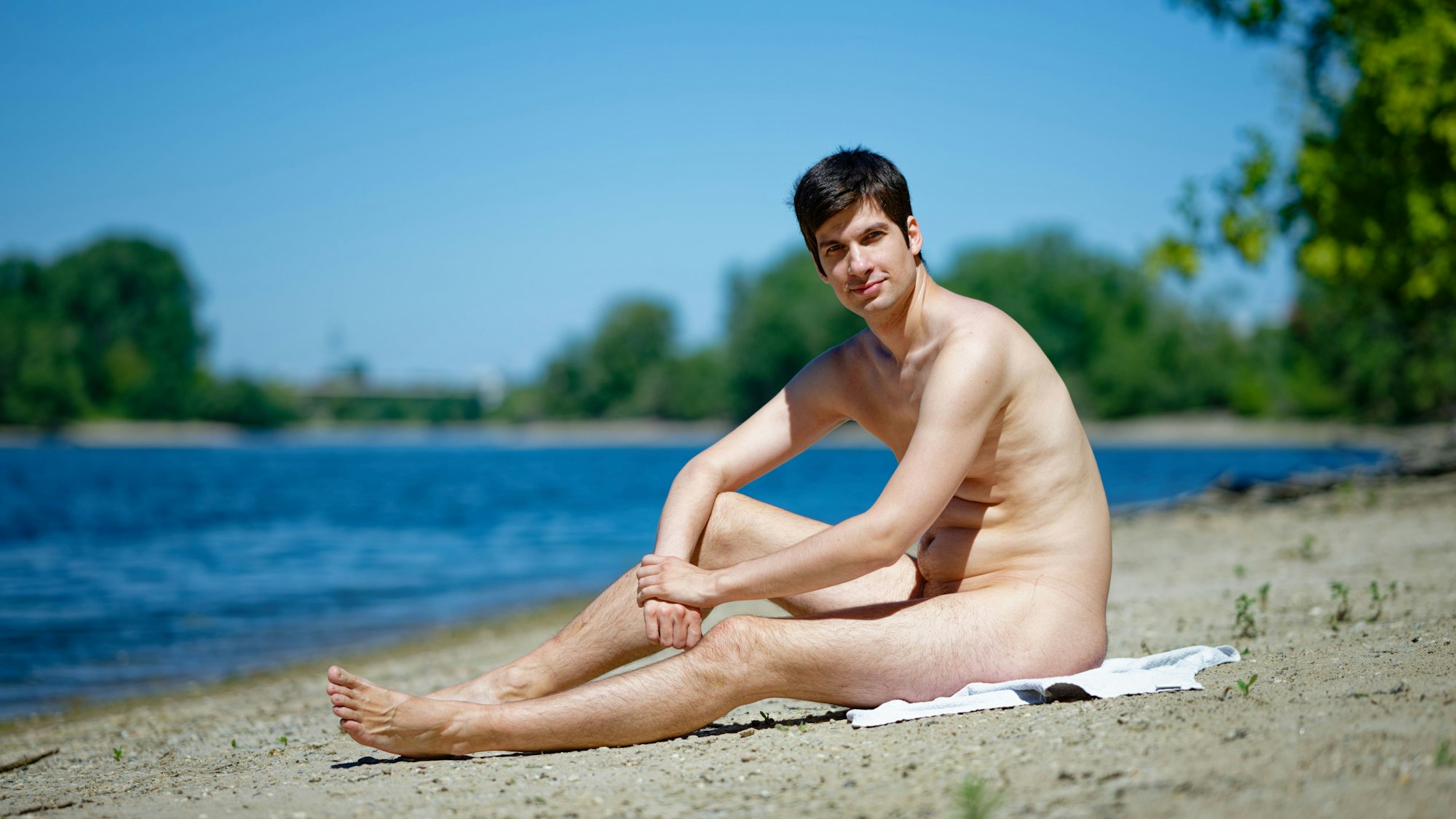 Mannheims Stadtrat Julien Ferrat (Wählervereinigung Die Mannheimer) sitzt am Ufer der Friesenheimer Insel. Ferrat plant ein Trainingscamp am örtlichen FKK-Strand für einen FKK-Swinger-Urlaub in Frankreich.