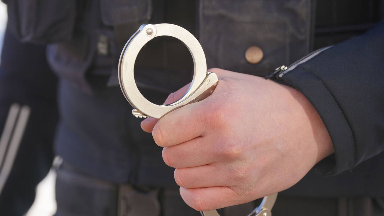 Ein Polizist hält Handschellen in der Hand.