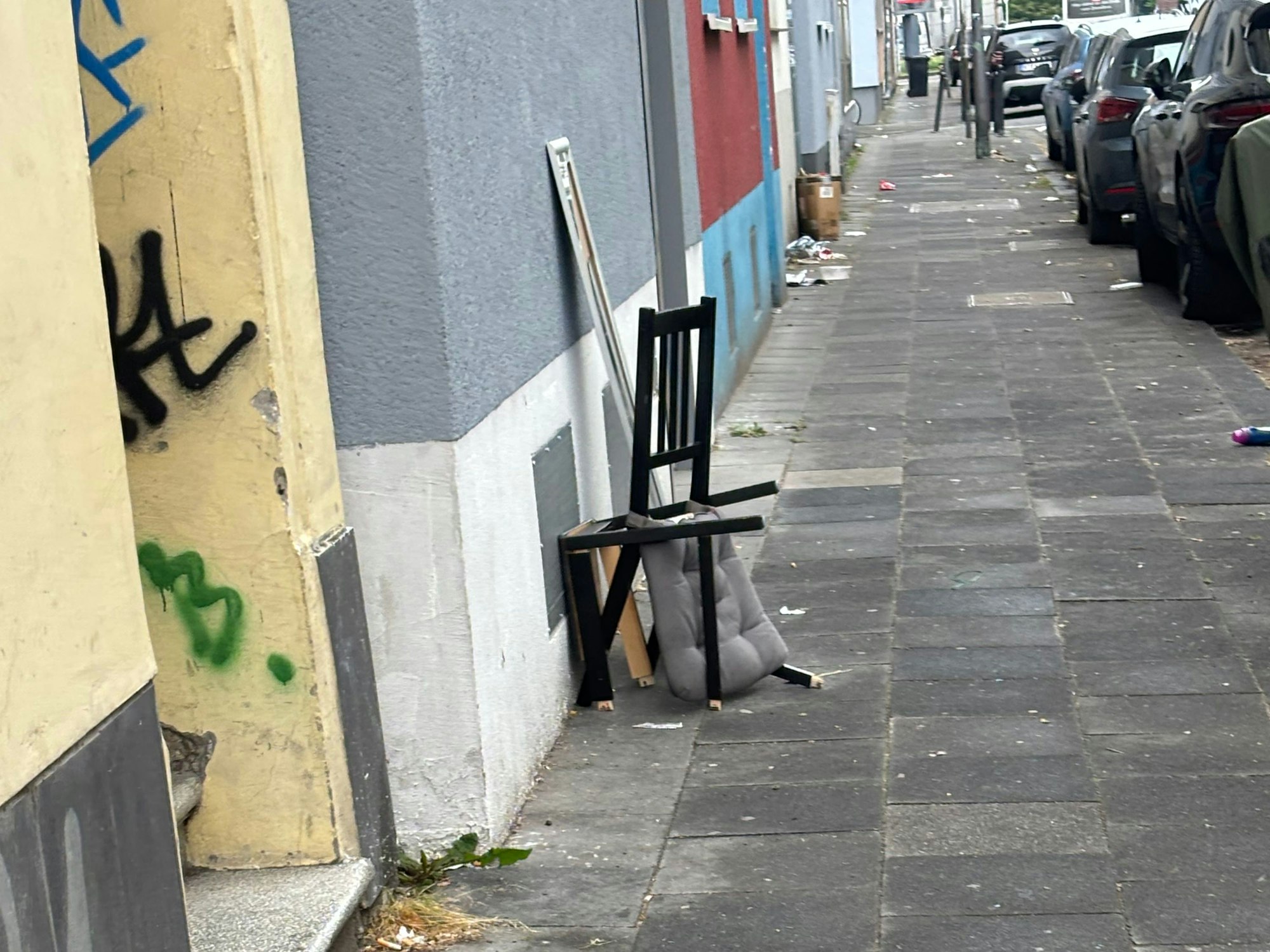 Ein kaputter Stuhl steht auf einem Gehweg.