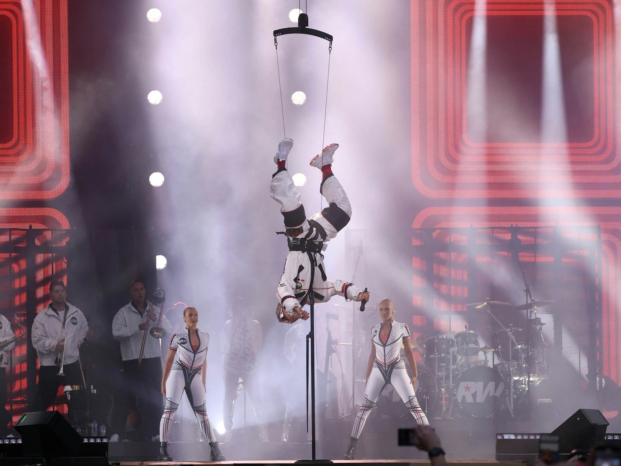 Robbie Williams wird per Seil auf die Bühne gelassen.