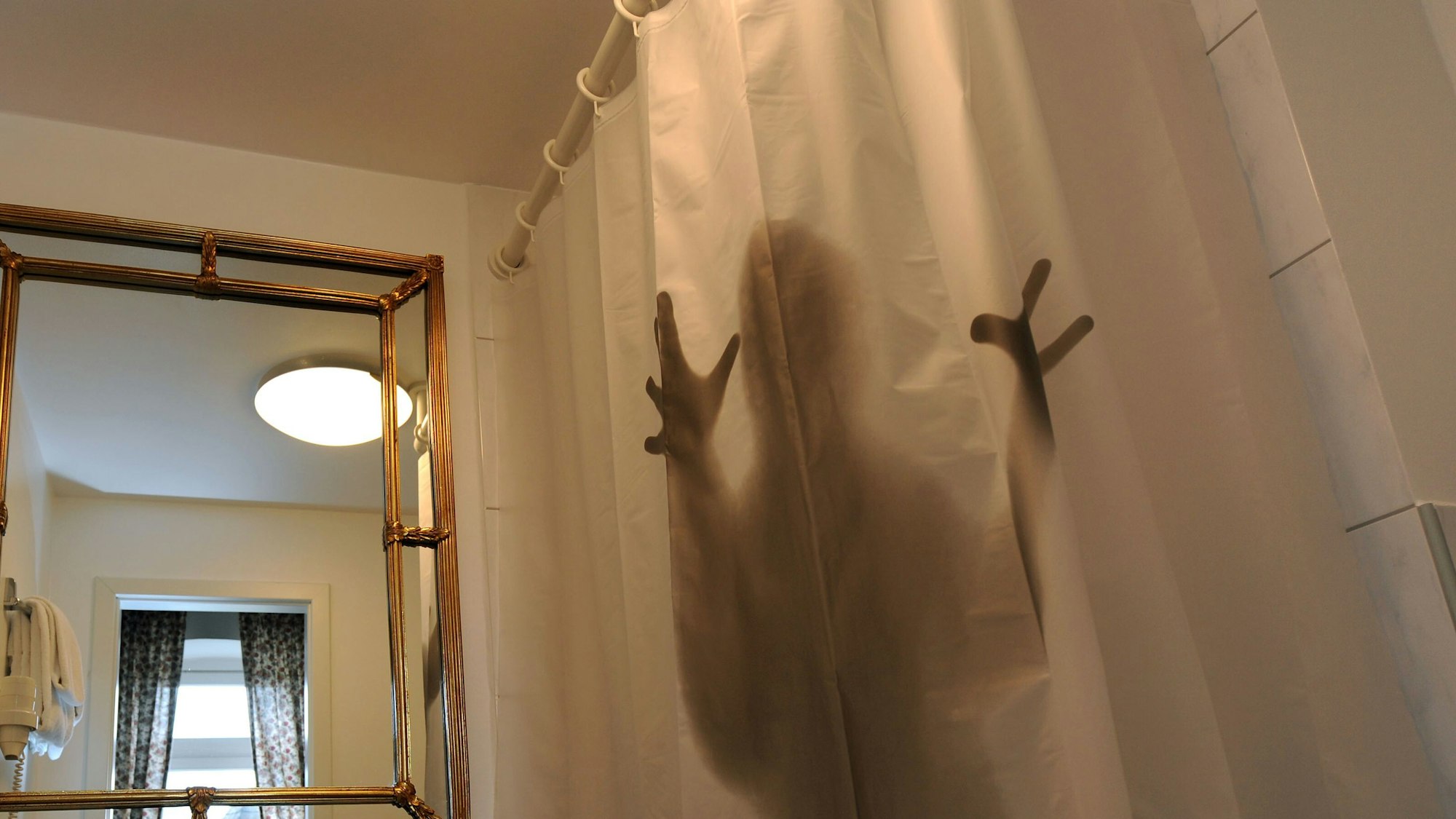 Die Silhouette eines Menschen hinter einem halbtransparenten Duschvorhang.