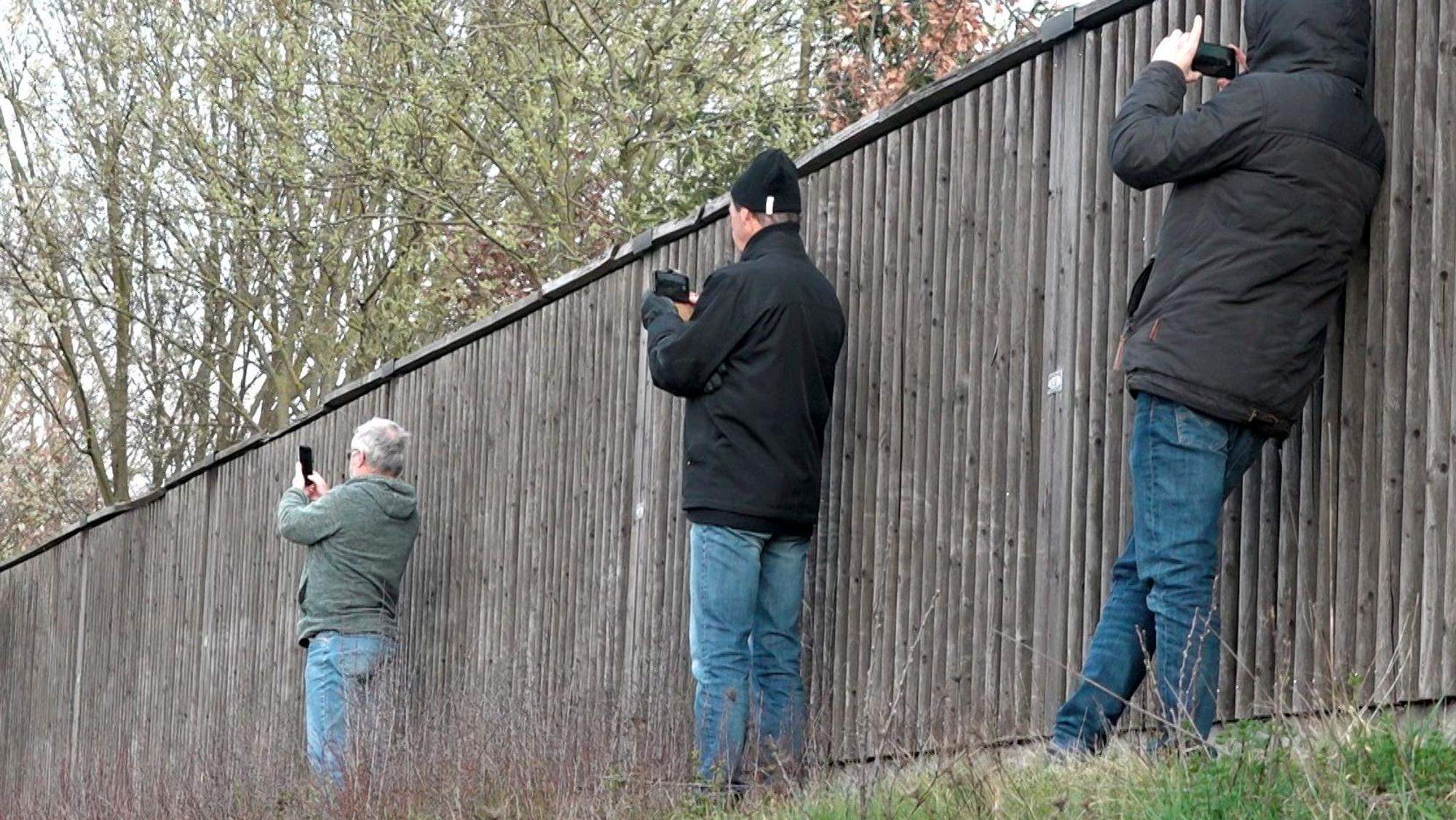 Schaulustige fotografieren in Bayern neben einer Lärmschutzwand mit ihren Smartphones eine Unfallstelle (Archivbild): Auch in NRW nimmt die Zahl der Gaffer bei Rettungseinsätzen zu.