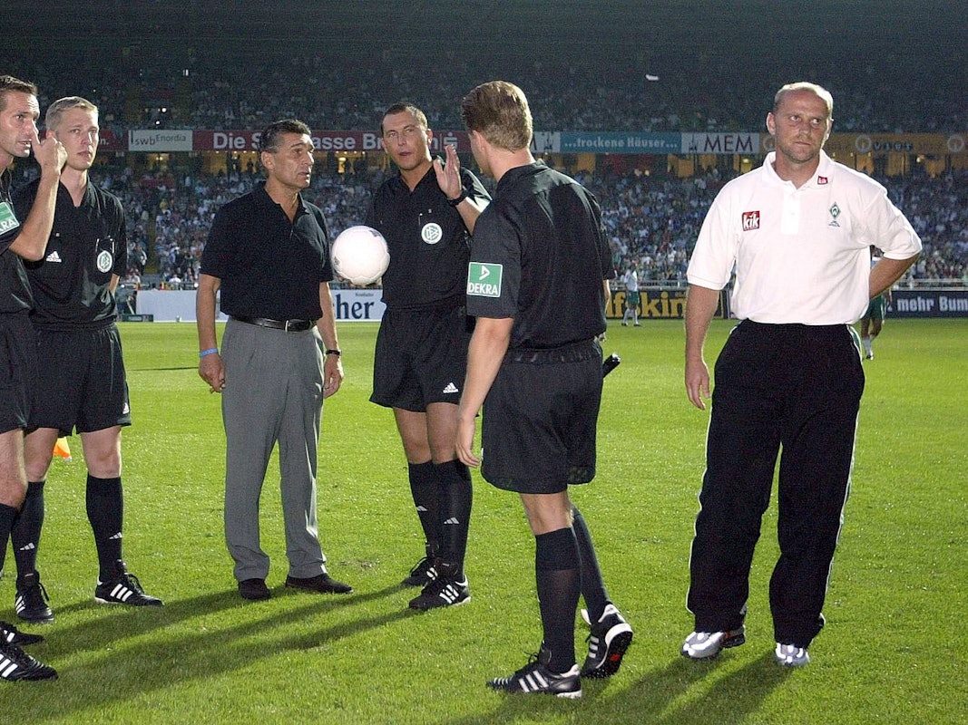 Rudi Assauer muss sich während des Stromausfalls in Bremen im August 2004 beim Schiedsrichtergespann erkundigen.