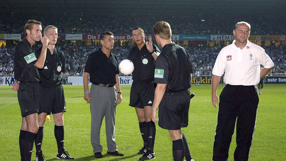 Rudi Assauer muss sich während des Stromausfalls in Bremen im August 2004 beim Schiedsrichtergespann erkundigen.