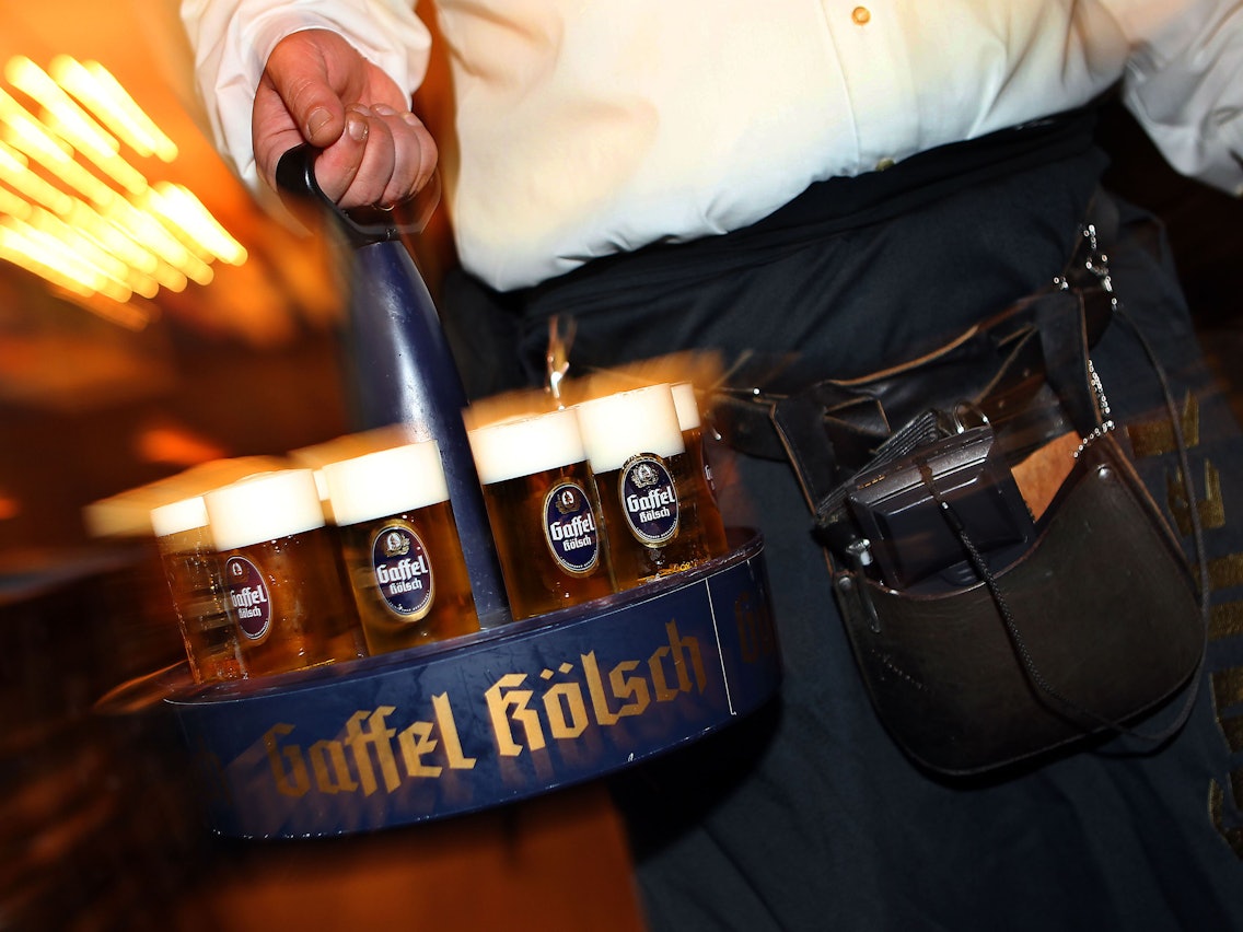 Ein Köbes (Kellner) trägt Kölsch-Bier im Kranz aus.