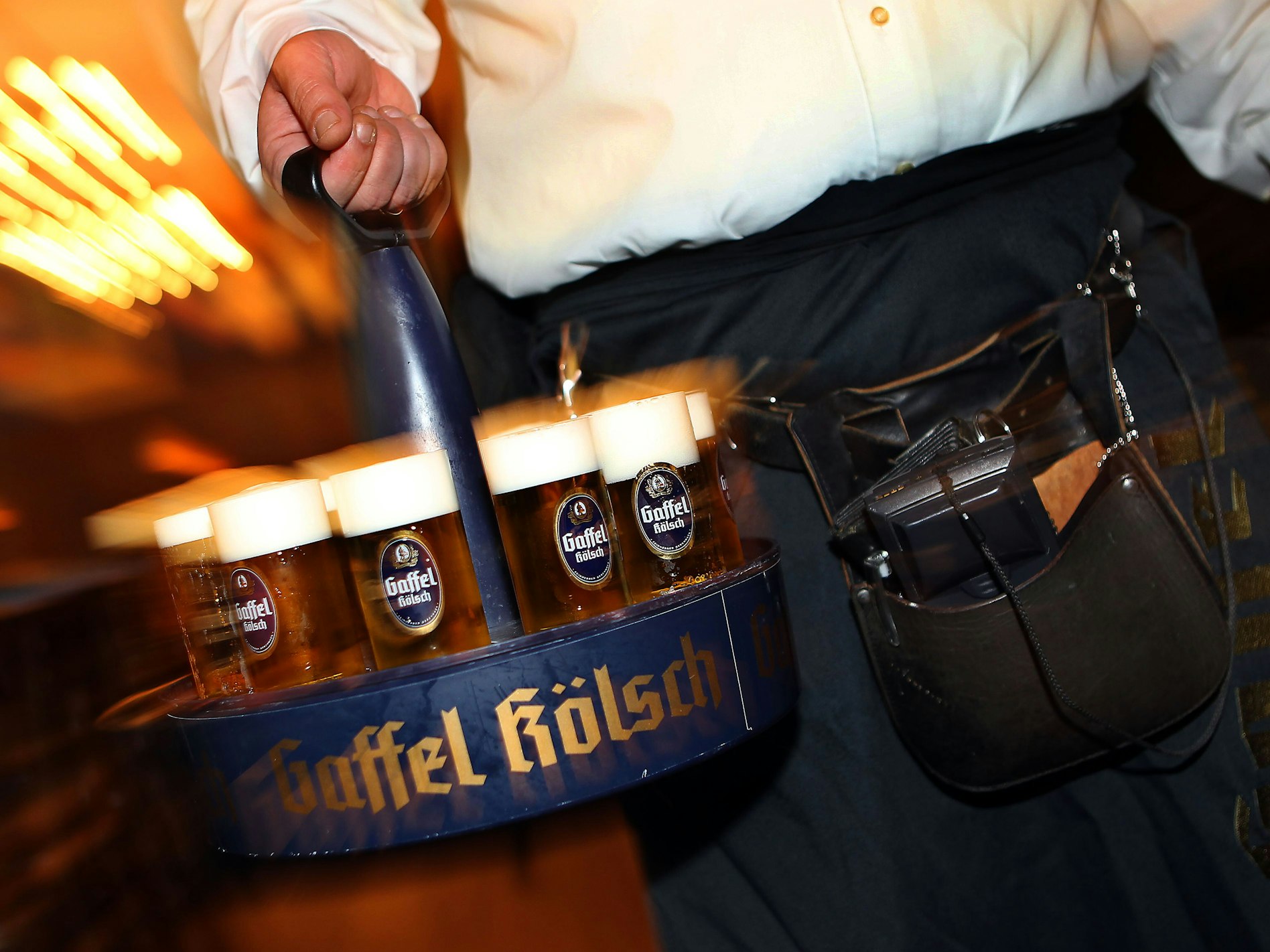 Ein Köbes (Kellner) trägt Kölsch-Bier im Kranz aus.