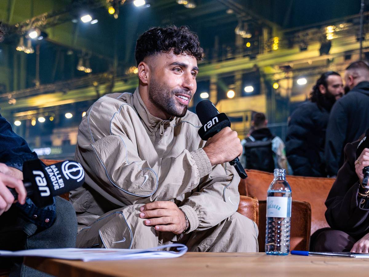 Nader El-Jindaoui sitzt mit Mikrofon auf der Couch bei der Baller League.