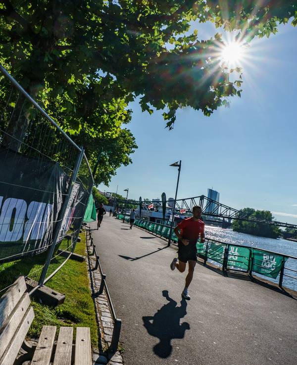 Ein Mann joggt in Frankfurt/Main am Mainufer vorbei.