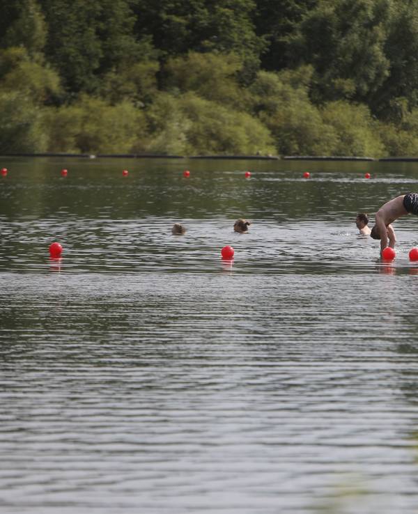 Menschen schwimmen und paddeln in einem Badesee