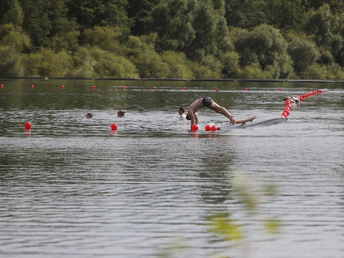 Menschen schwimmen und paddeln in einem Badesee