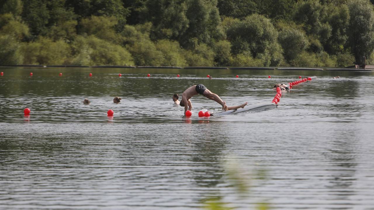 Menschen schwimmen und paddeln in einem Badesee