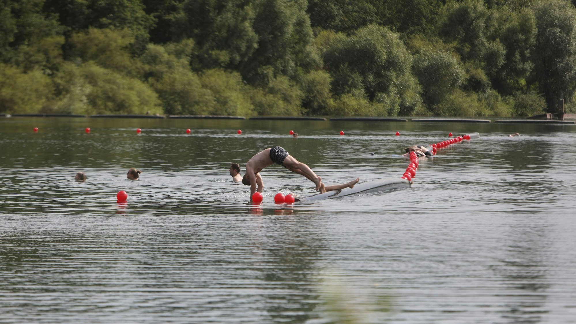 Menschen schwimmen und paddeln in einem Badesee