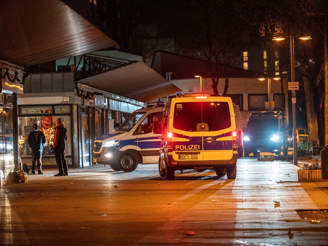 Drei Polizeifahrzeuge stehen nachts vor einem Kiosk.