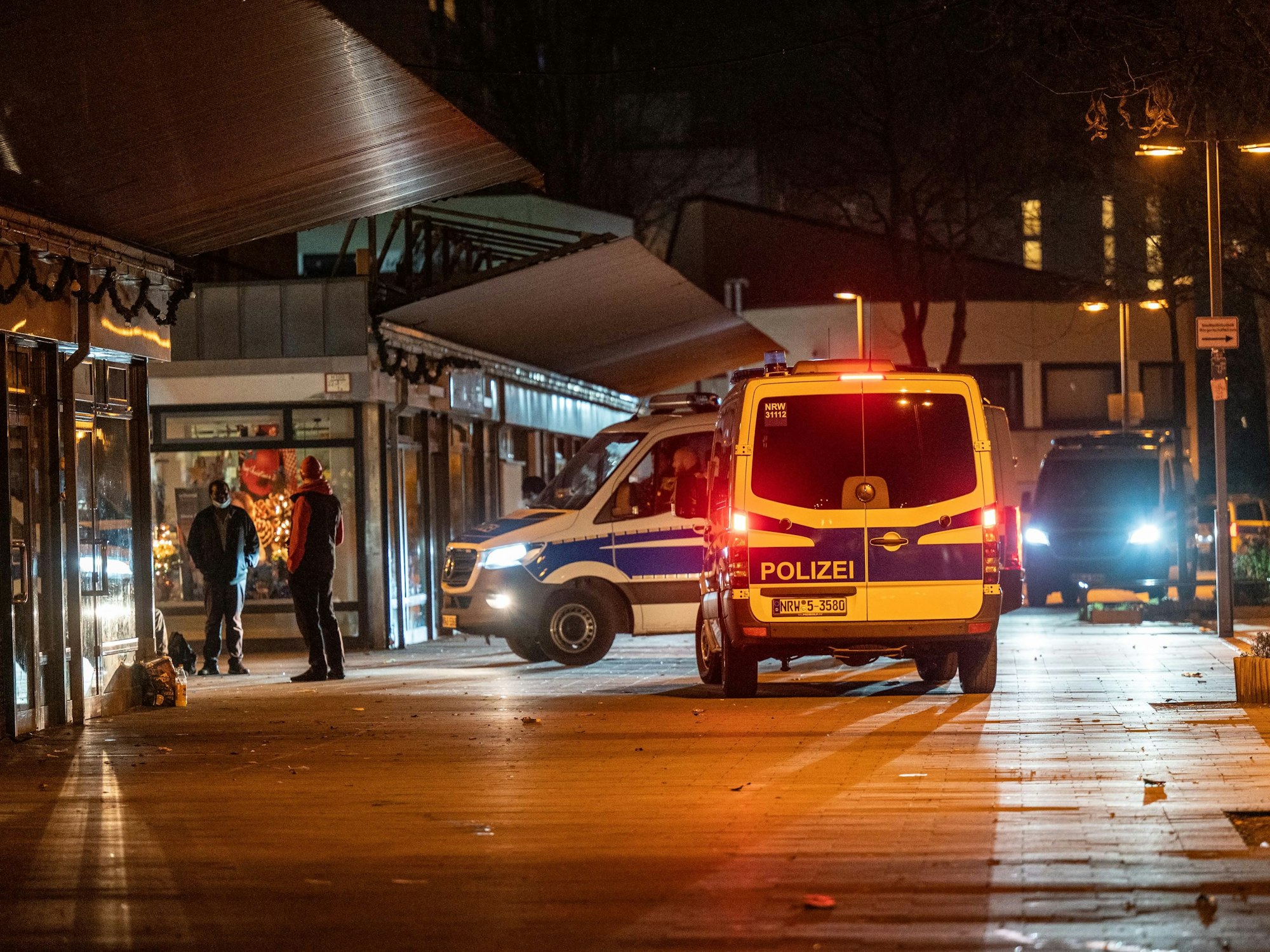 Drei Polizeifahrzeuge stehen nachts vor einem Kiosk.