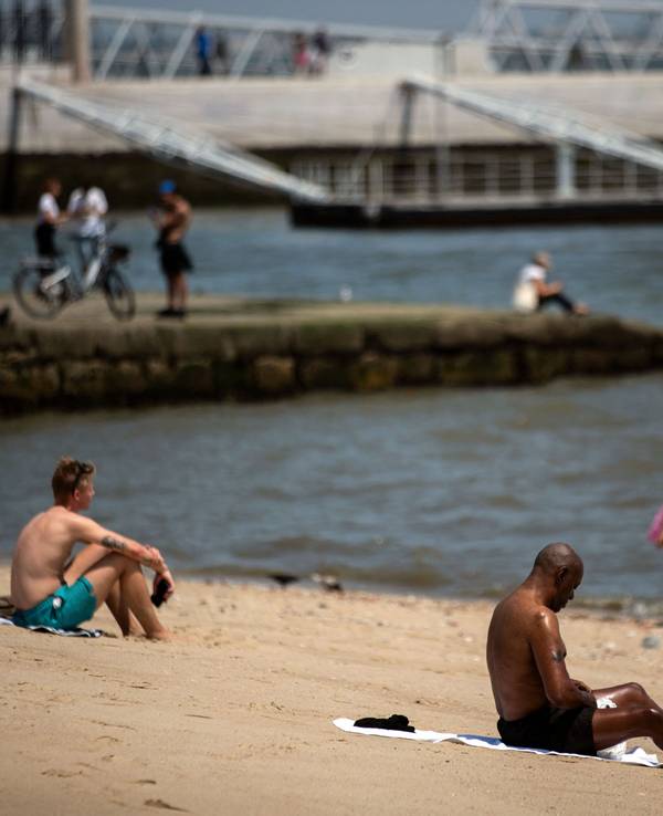 Menschen sonnen sich während der Hitzewelle in Lissabon am 29. Juni 2025 am Fluss Tajo.