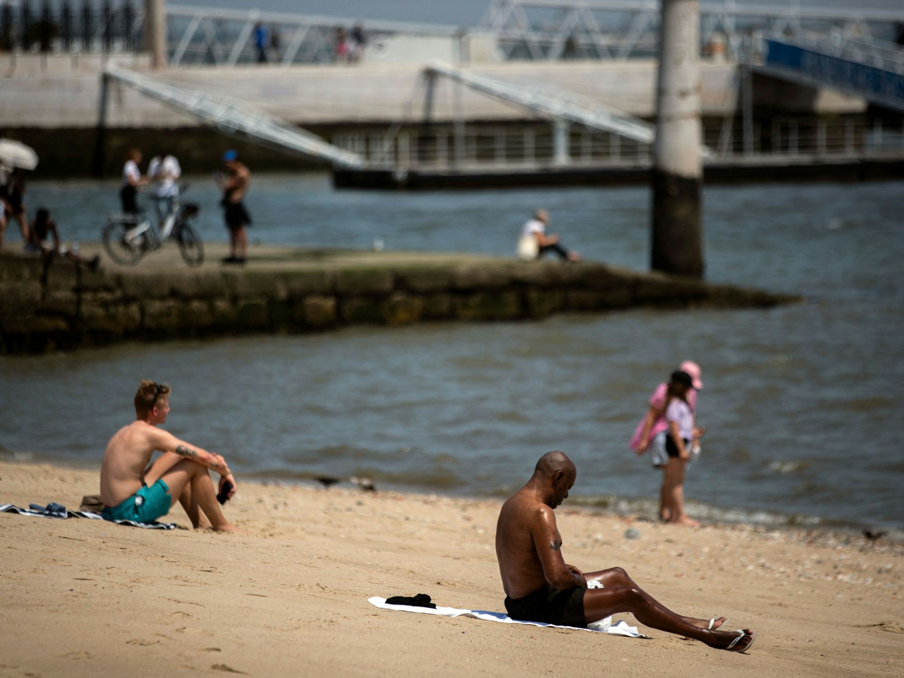 Menschen sonnen sich während der Hitzewelle in Lissabon am 29. Juni 2025 am Fluss Tajo.