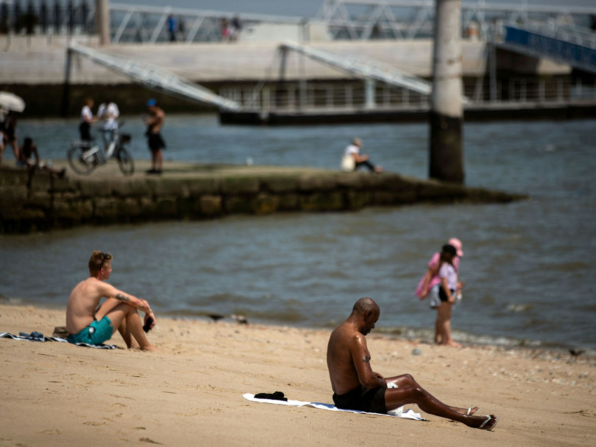 Menschen sonnen sich während der Hitzewelle in Lissabon am 29. Juni 2025 am Fluss Tajo.