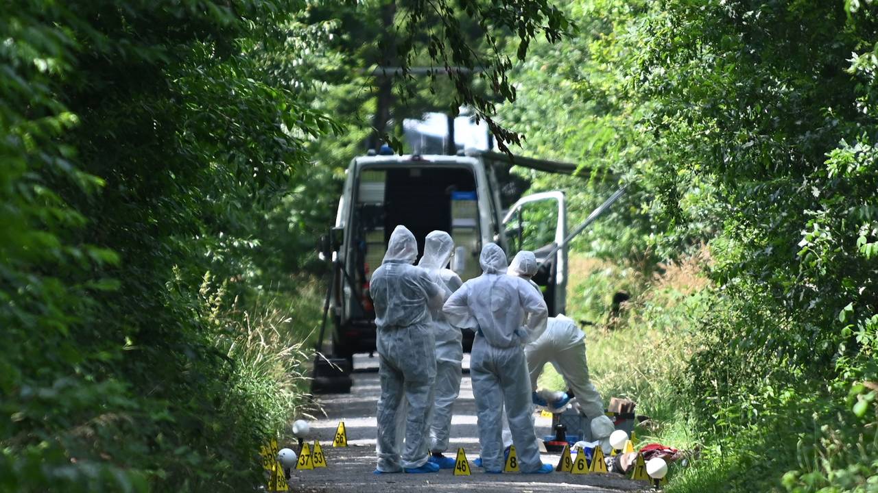 Ermittler stehen auf einem Weg. Polizisten haben nach einem Hinweis von Passanten an einem Waldweg eine tote Frau und ein totes Kleinkind entdeckt.