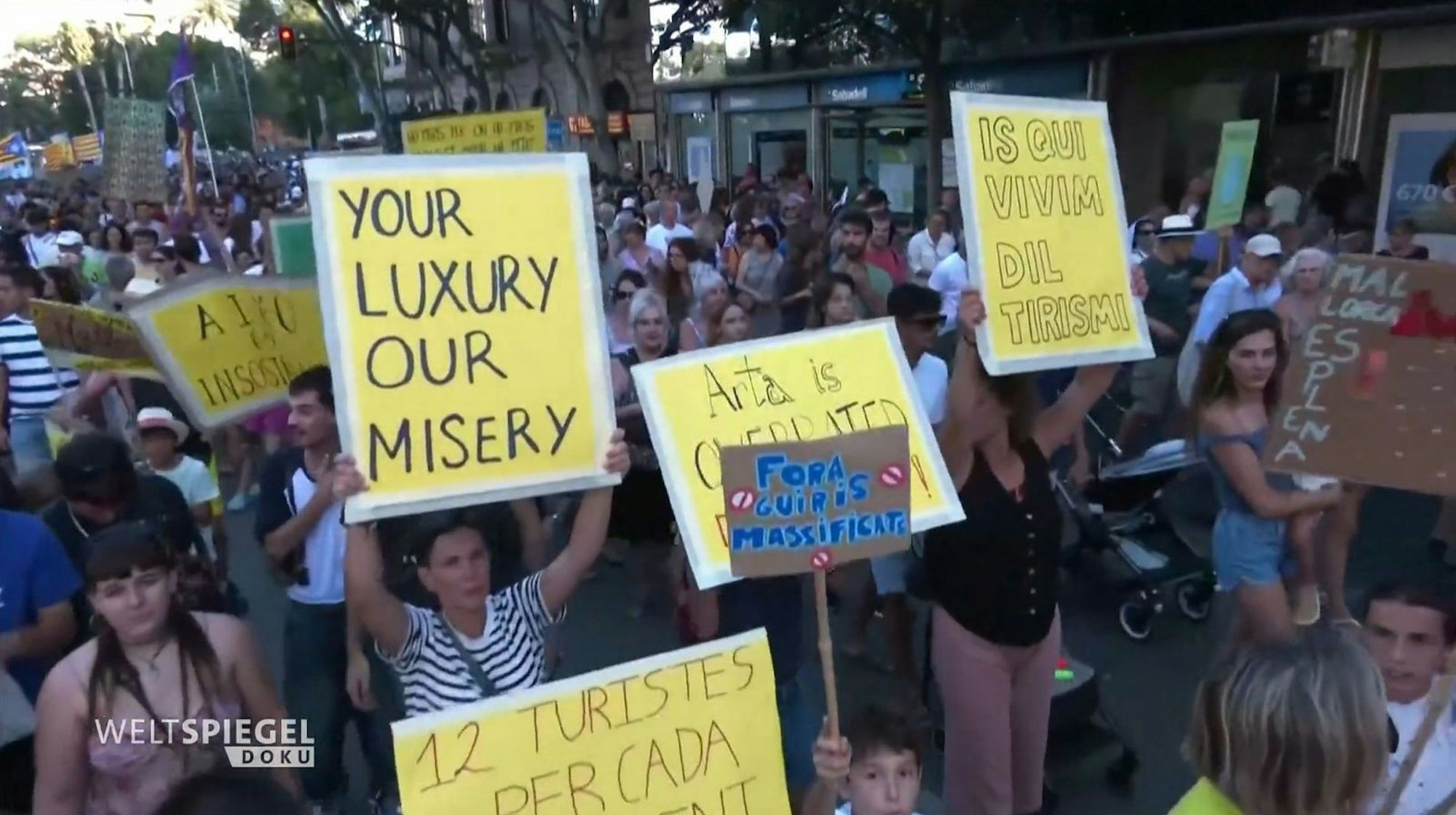 „Euer Luxus ist unser Elend“ - mit Bannern wie diesen demonstrierten zuletzt mallorquinische Einheimische gegen den inflationären Zuzug von Superreichen. (Bild: ARD / HR)