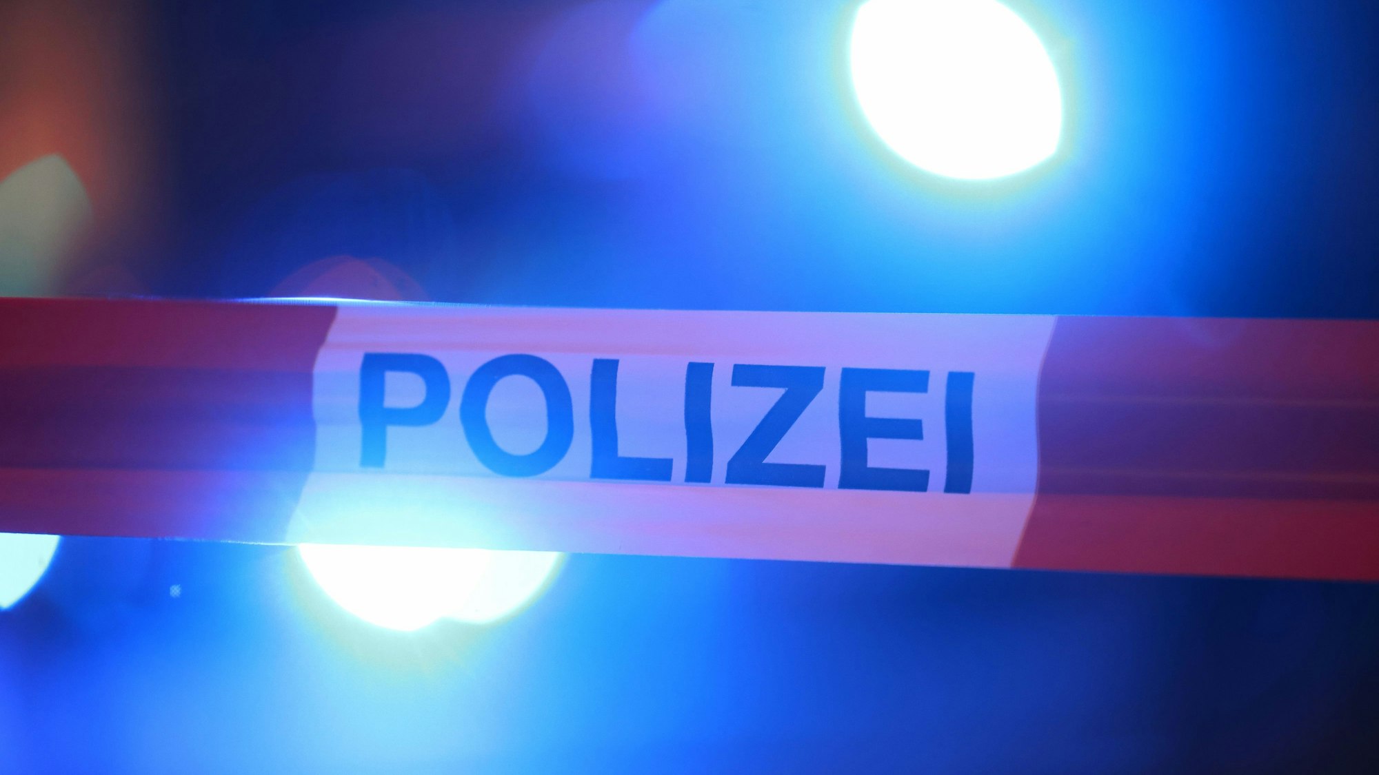 Ein Polizist führt einen Mann in Handschellen ab.