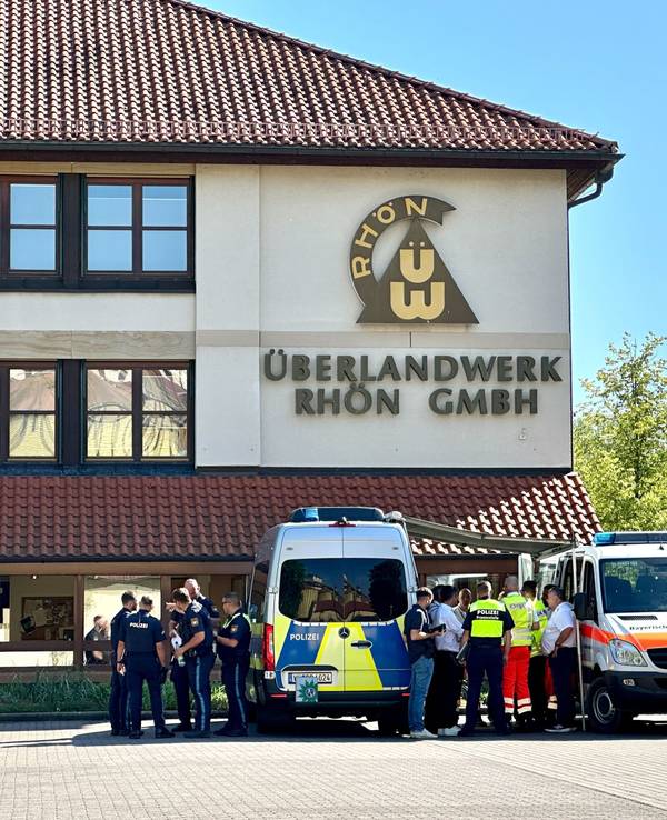 Polizei und Rettungskräfte stehen auf dem Gelände des regionalen Netzbetreibers Überlandwerk Rhön. Ein 21-Jähriger hat in der Firma eine Kollegin getötet und zwei weitere Kollegen schwer verletzt.