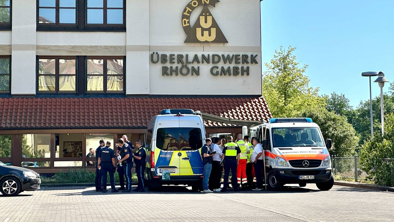Polizei und Rettungskräfte stehen auf dem Gelände des regionalen Netzbetreibers Überlandwerk Rhön. Ein 21-Jähriger hat in der Firma eine Kollegin getötet und zwei weitere Kollegen schwer verletzt.