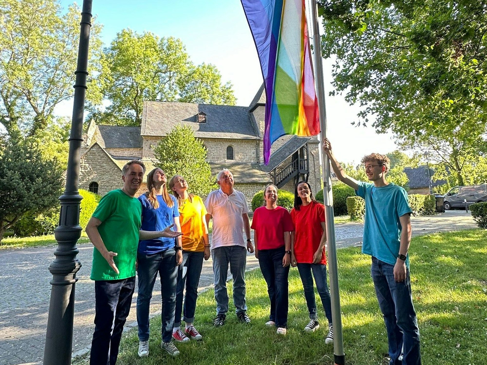 Der Jugendchor hisst die Regenbogenflagge an der Kirche.