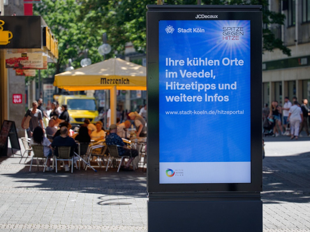 Die Stadt Köln wirbt auf einem Standmonitor für das Hitzeportal mit Tipps bei heißem Wetter.