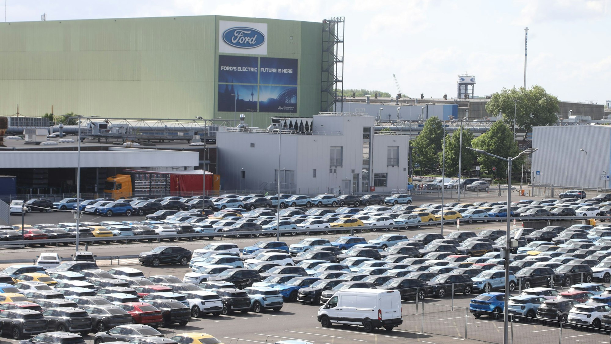 Vor dem Fordwerk stehen unzählige Autos.