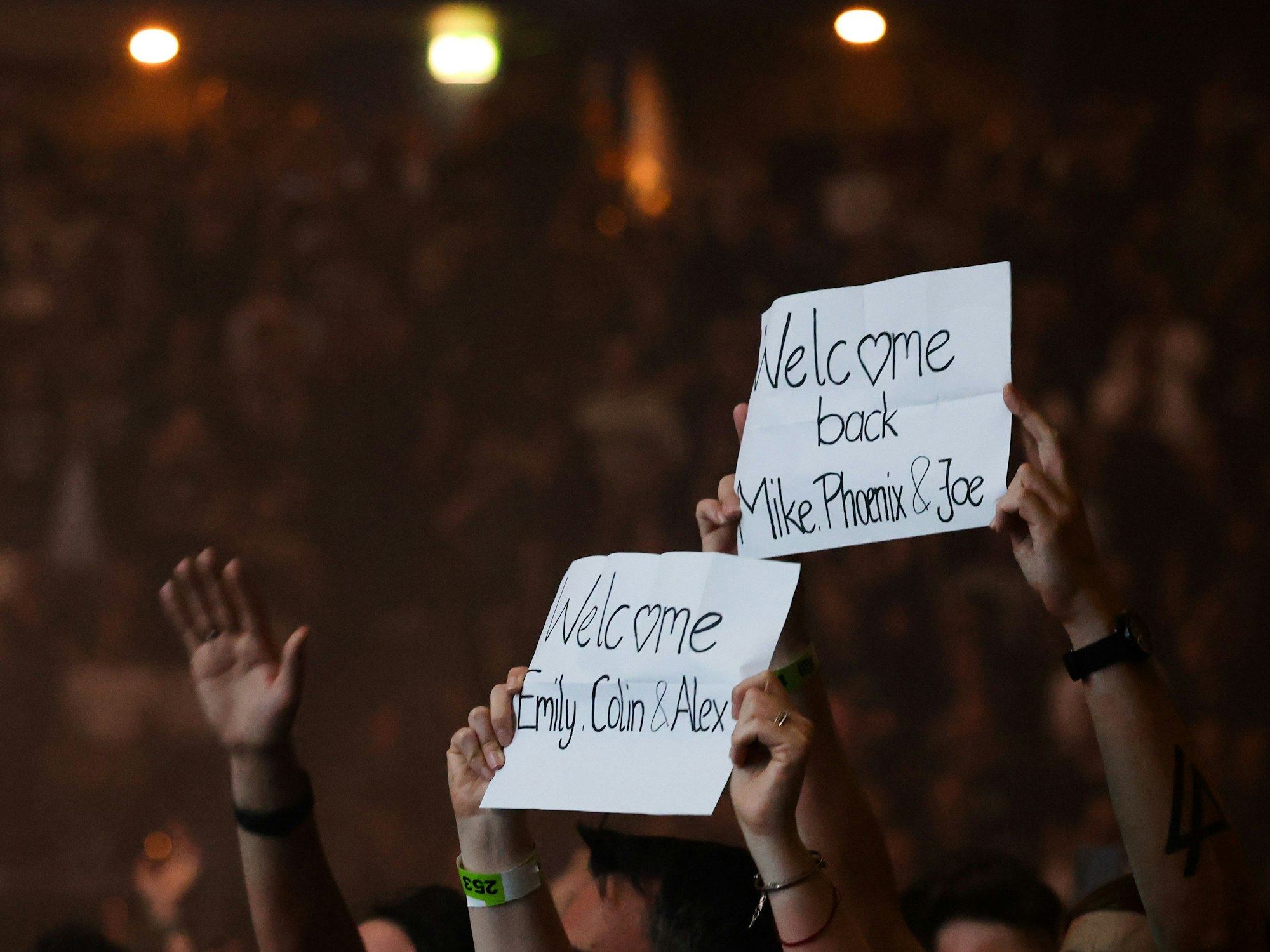 Fans halten Zettel mit dem Text „Welcome back“ bei einem Konzert der US-Band Linkin Park hoch.