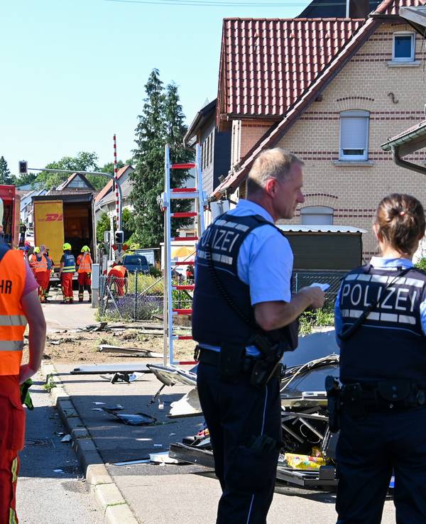 Einsatzkräfte der Feuerwehr und Polizei stehen an der Unfallstelle in Amstetten, nachdem ein Lastwagen, der auf der B10 in Richtung Geislingen fuhr, von der Fahrbahn abgekommen war und in das Gebäude einer Gaststätte gekracht war. Ein Mann und der 47-jährige Lastwagenfahrer wurden schwer verletzt.
