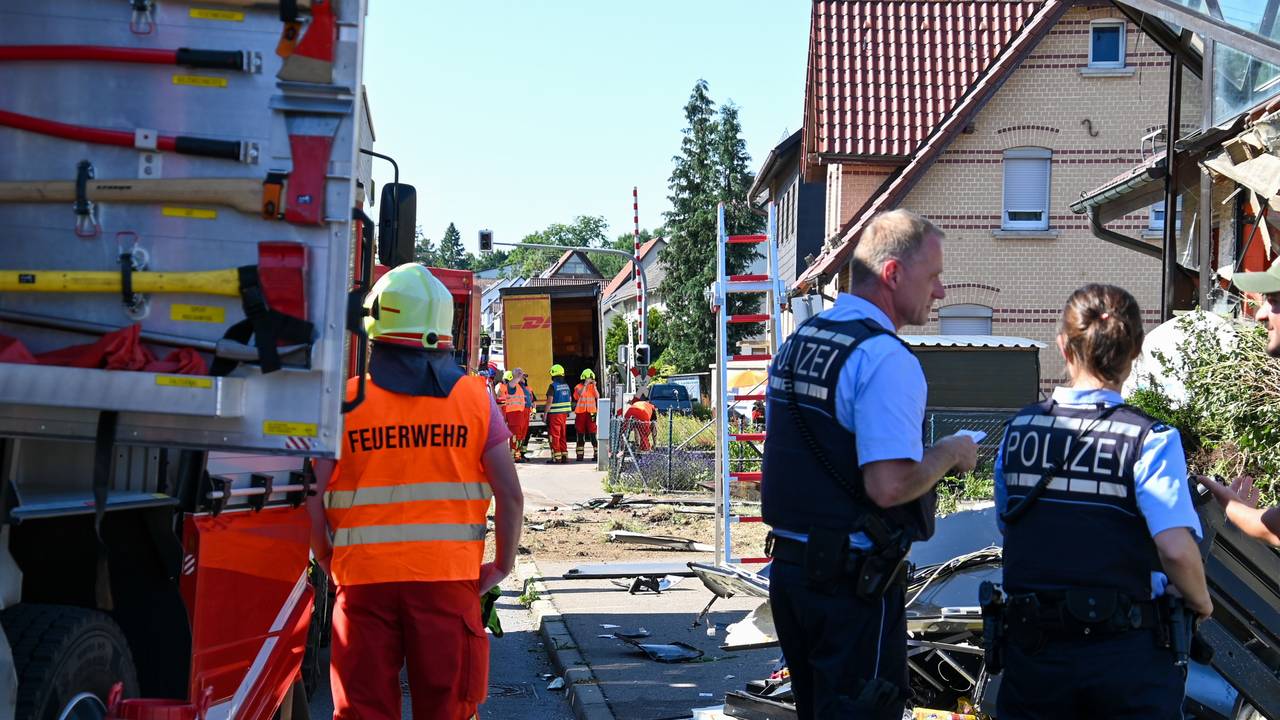 Einsatzkräfte der Feuerwehr und Polizei stehen an der Unfallstelle in Amstetten, nachdem ein Lastwagen, der auf der B10 in Richtung Geislingen fuhr, von der Fahrbahn abgekommen war und in das Gebäude einer Gaststätte gekracht war. Ein Mann und der 47-jährige Lastwagenfahrer wurden schwer verletzt.