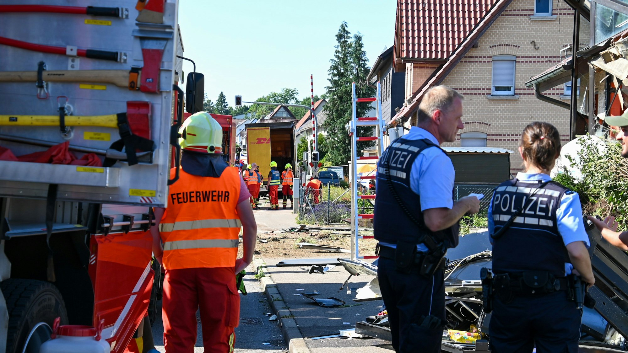 Einsatzkräfte der Feuerwehr und Polizei stehen an der Unfallstelle in Amstetten, nachdem ein Lastwagen, der auf der B10 in Richtung Geislingen fuhr, von der Fahrbahn abgekommen war und in das Gebäude einer Gaststätte gekracht war. Ein Mann und der 47-jährige Lastwagenfahrer wurden schwer verletzt.