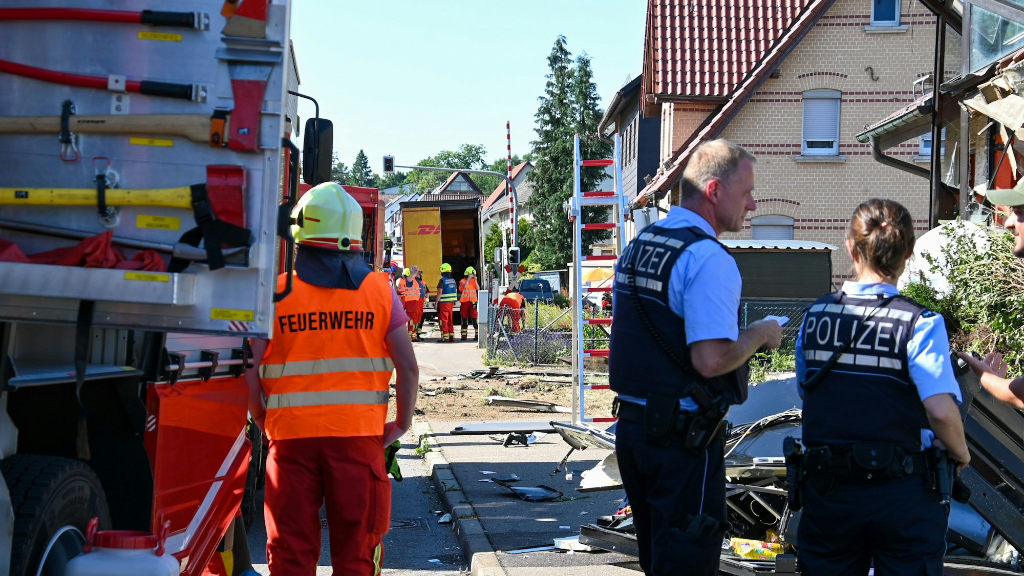 Einsatzkräfte der Feuerwehr und Polizei stehen an der Unfallstelle in Amstetten, nachdem ein Lastwagen, der auf der B10 in Richtung Geislingen fuhr, von der Fahrbahn abgekommen war und in das Gebäude einer Gaststätte gekracht war. Ein Mann und der 47-jährige Lastwagenfahrer wurden schwer verletzt.