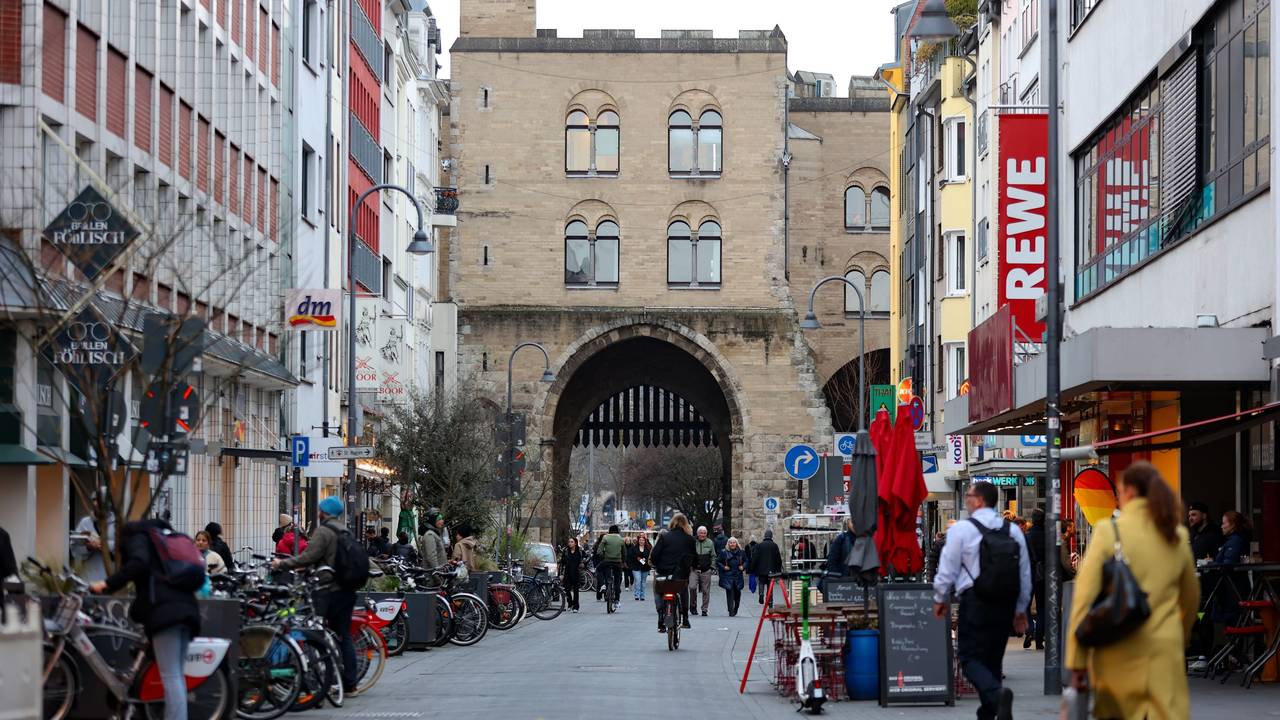 Eine Straße, die mit Gebäuden gesäumt ist, führt auf eine historische Burg mit einem Tor zu.