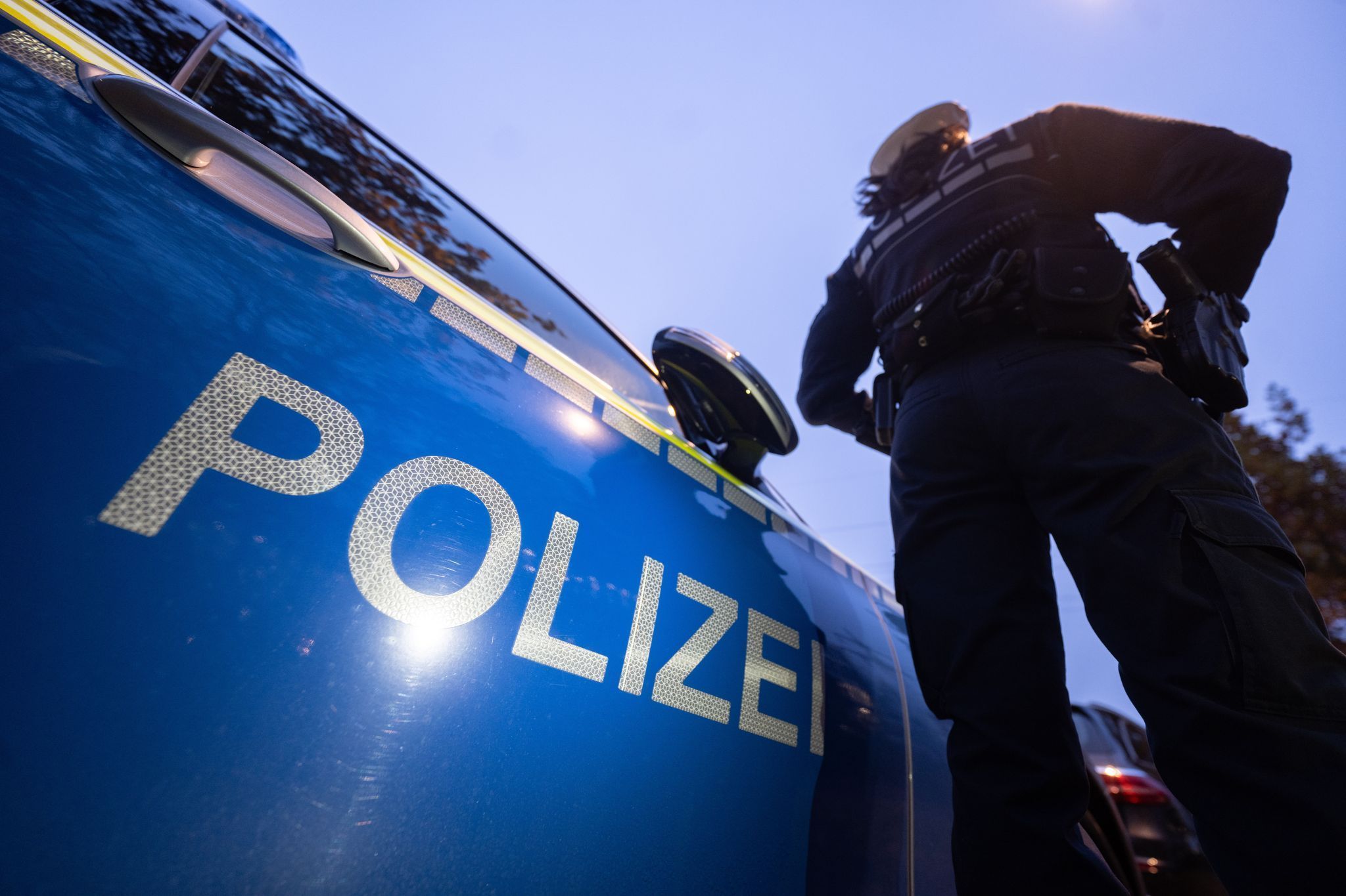 Ein Polizist steht neben einem Streifenwagen.