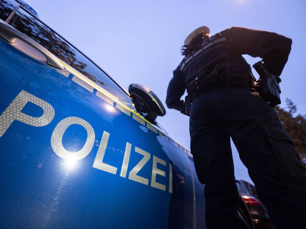 Ein Polizist steht neben einem Streifenwagen.