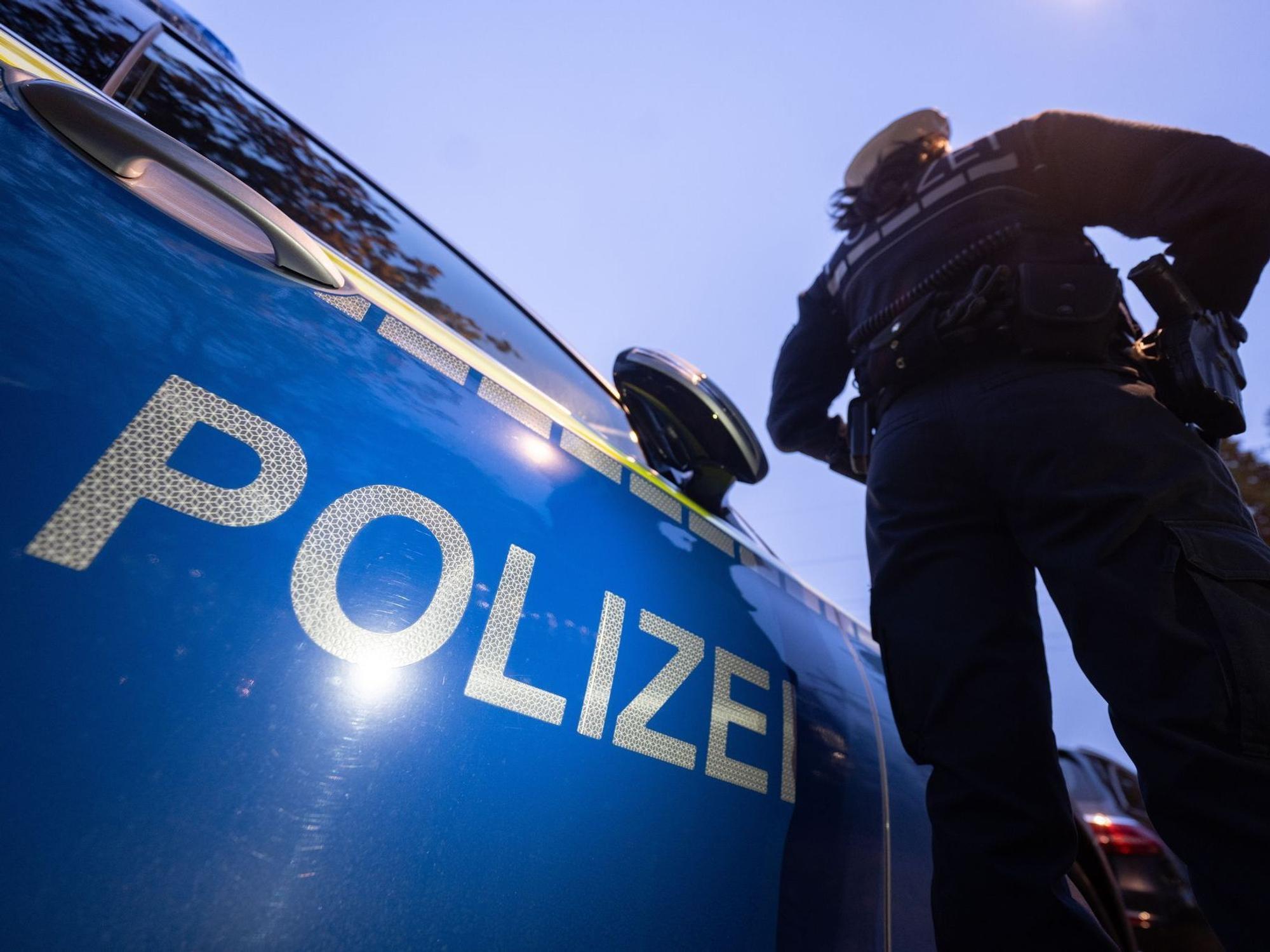 Ein Polizist steht neben einem Streifenwagen.